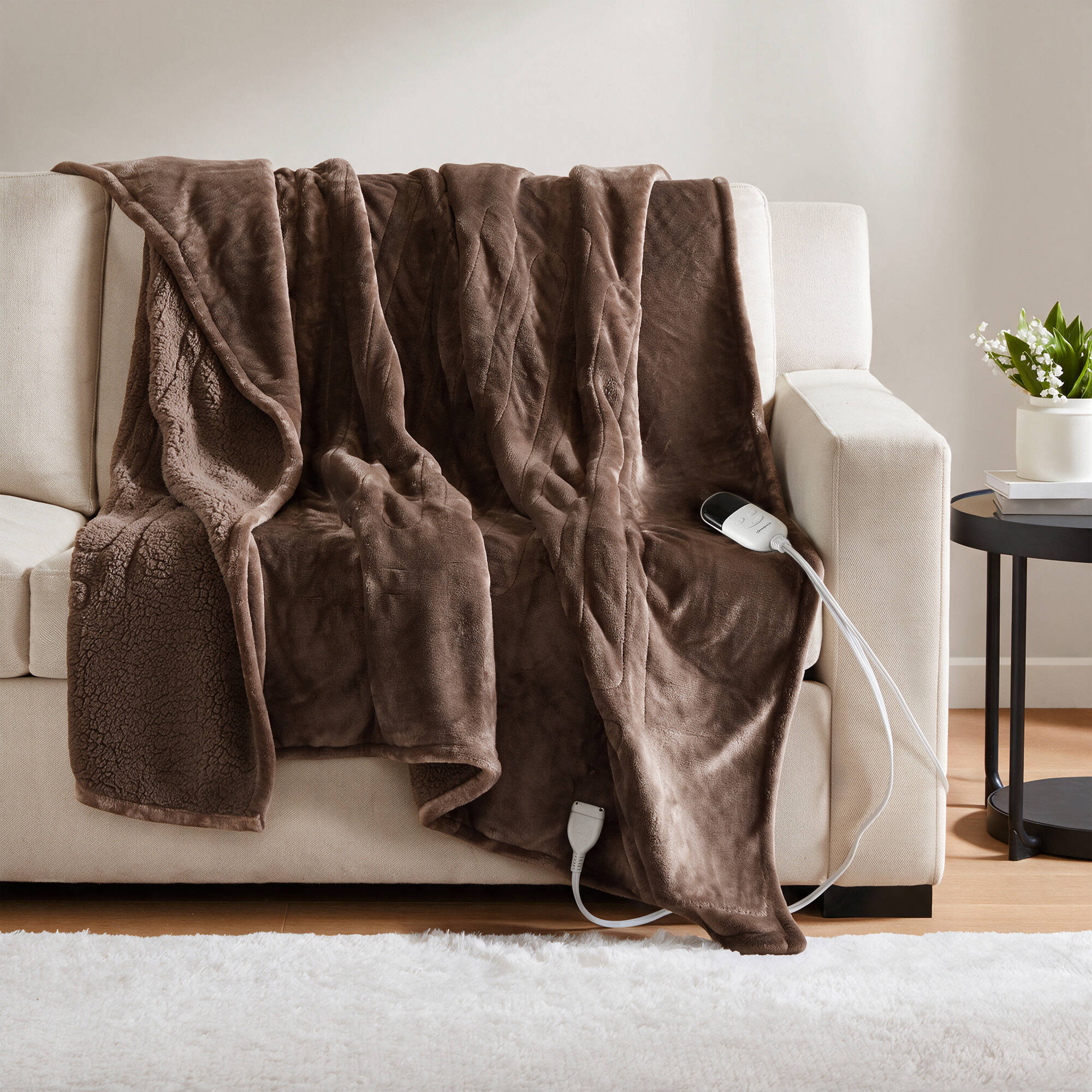 Brown-looking Beautyrest BR54-0310N heated throw draped over a sofa with a visible wired controller
