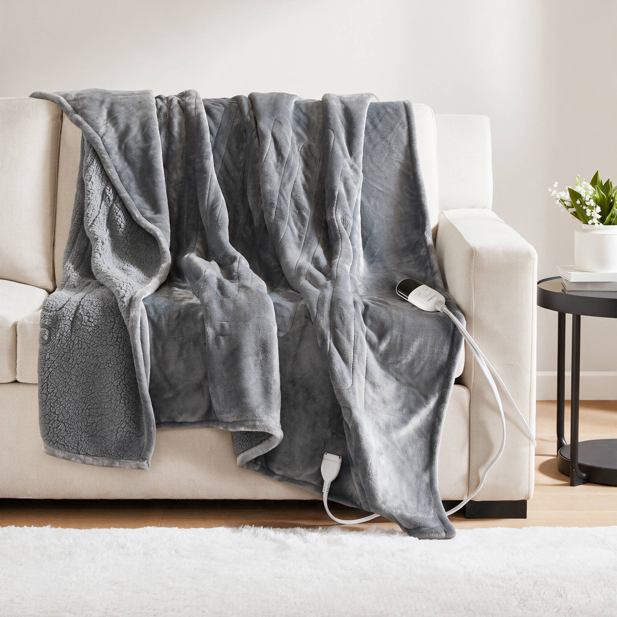 Grey-toned Beautyrest BR54-0415N heated throw draped over a sofa with a visible wired controller
