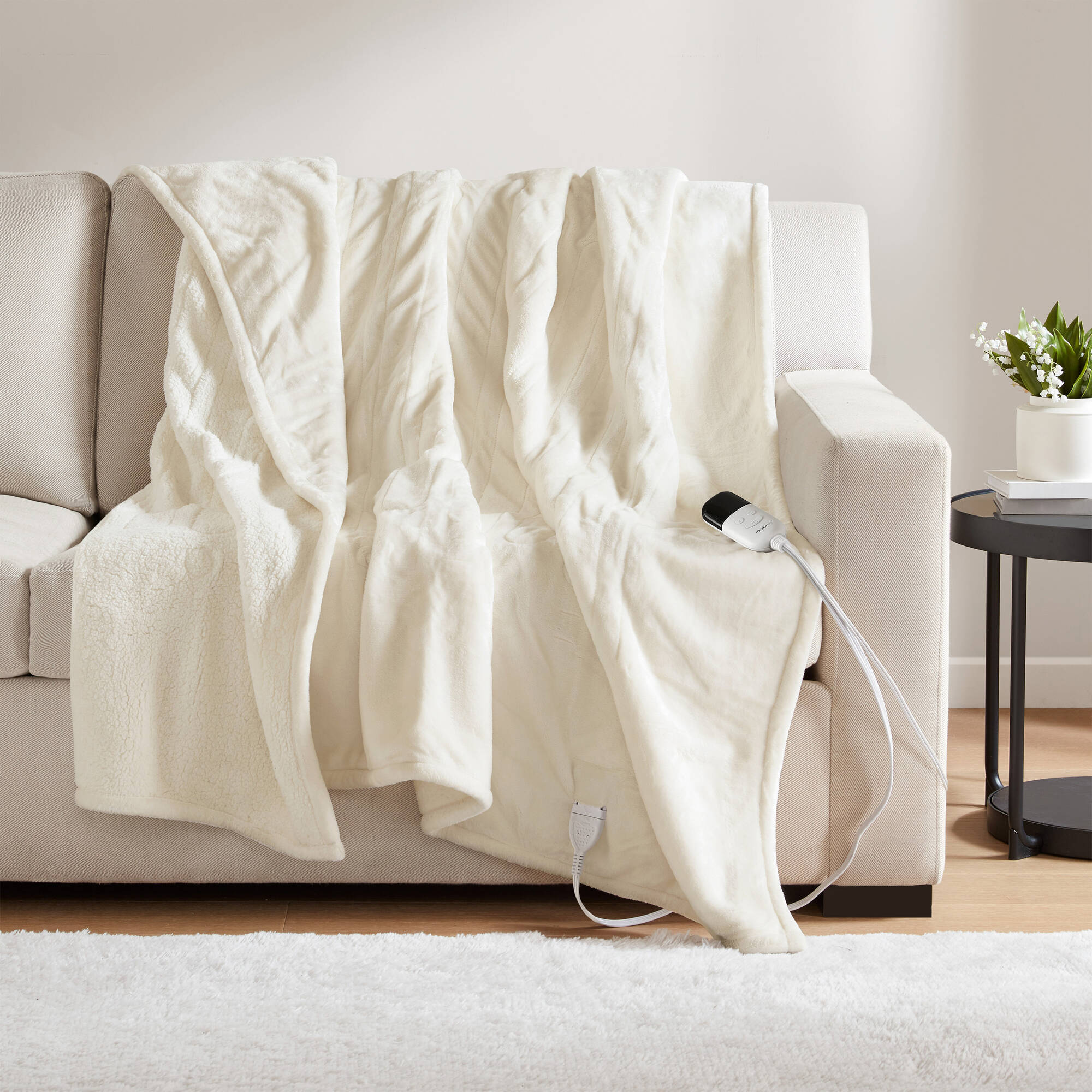Ivory-looking Beautyrest BR54-0662N heated throw draped over a sofa with a visible wired controller