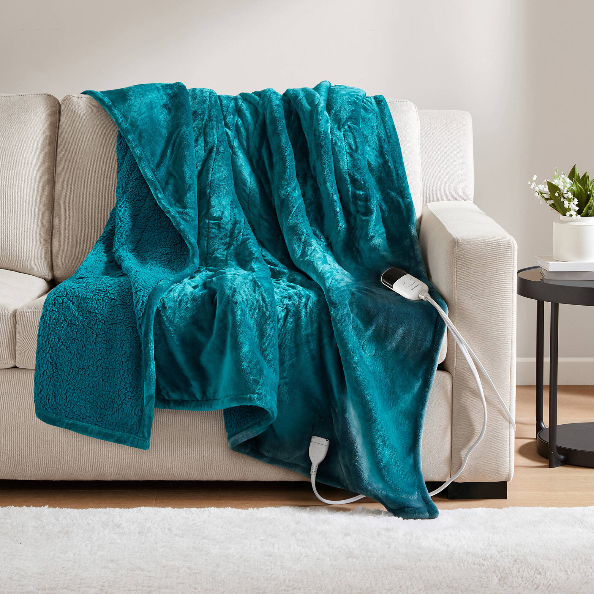 Teal Beautyrest BR54-1926N heated throw draped over a sofa with a visible wired controller