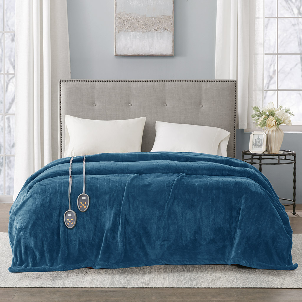 Teal Beautyrest Plush heated blanket in a staged bedroom; two wired controller heads are visible, but the image does not identify size or package