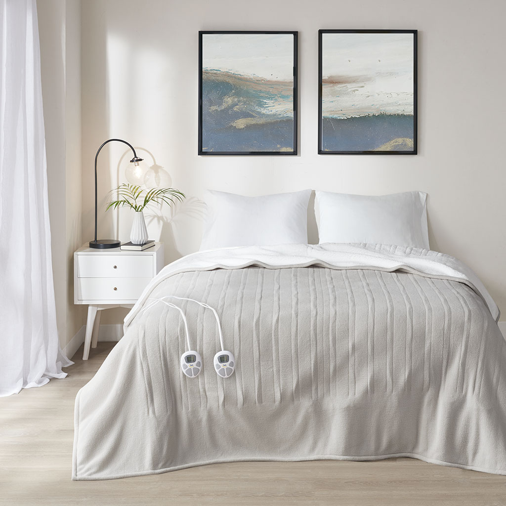 Serta Fleece to Sherpa heated bed blanket in Tan, staged over a bed with two wired controls; family image, not size-specific.