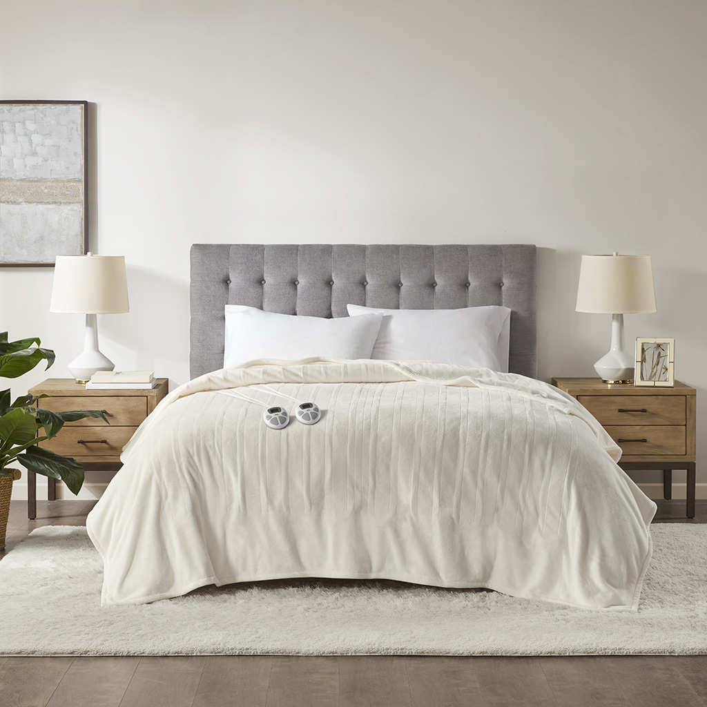 Ivory Serta Plush Heated Blanket staged on a bed