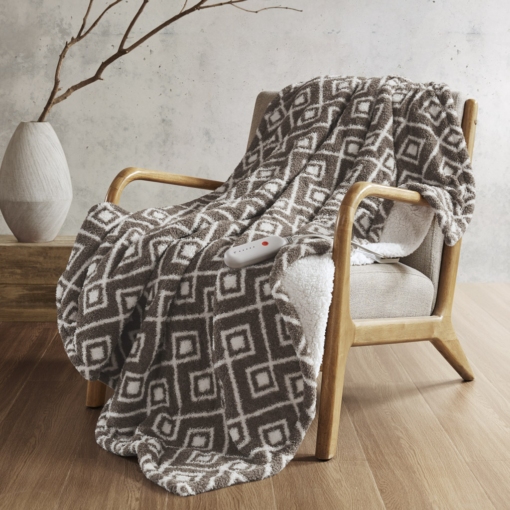 Brown Geo geometric Sharper Image heated throw draped over a chair with the Sherpa-like reverse visible