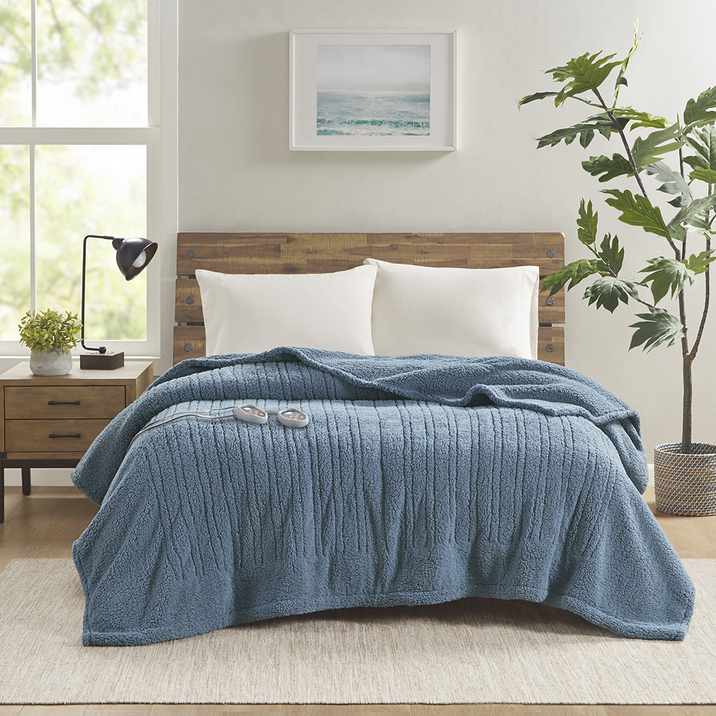 Blue True North Sherpa bed blanket displayed on a bed with two controllers