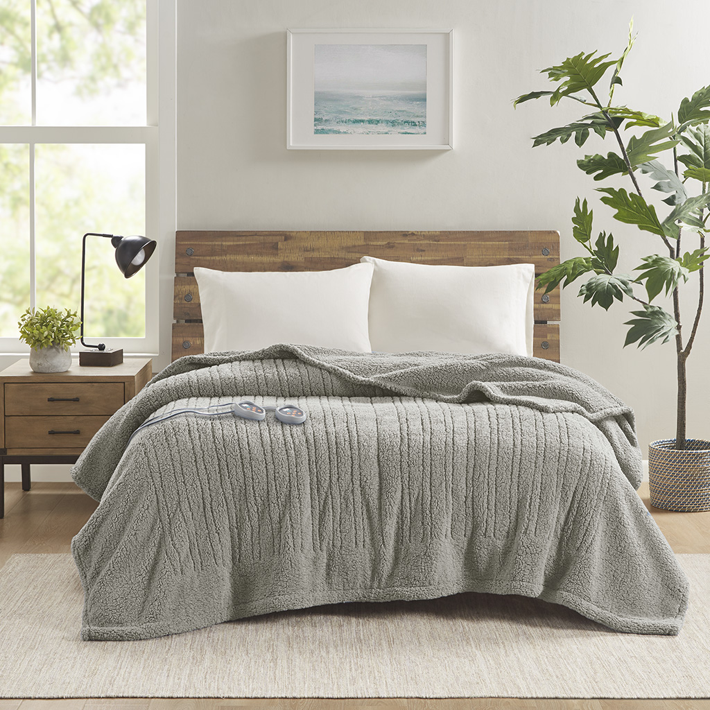 Grey True North Sherpa bed blanket displayed on a bed with two controllers